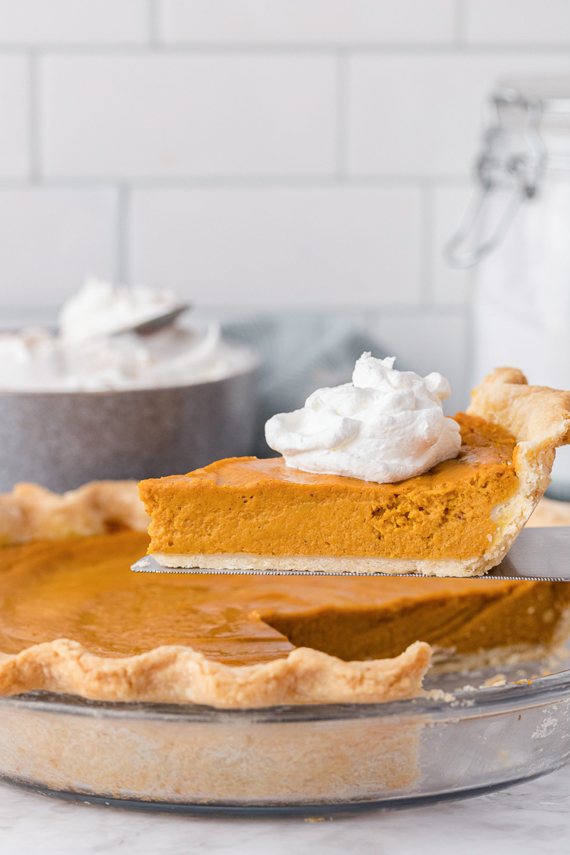 Sweet potato pie with slice being lifted up.