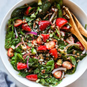 Closeup of strawberry spinach salad in white bowl.