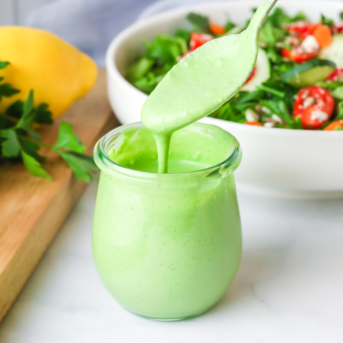 Green goddess dressing with a spoon.